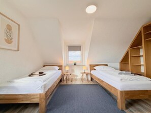 A room with two wooden beds, a small table, and a window. - Pension Bockenem (Bockenem)