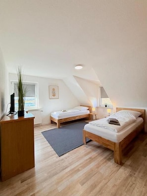 A small, well-lit room with two wooden beds, a desk, and a radiator. - Pension Bockenem (Bockenem)