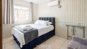 A bedroom with a bed, a window, an air conditioning unit, and a small table. - House w/ Barbecue 600 m From the Beach Nus0636 (Picarras)