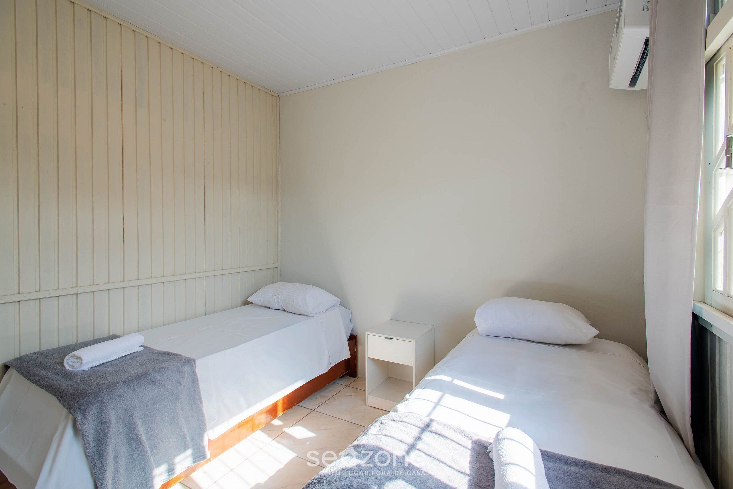 Une chambre avec deux lits simples, une petite table de chevet et une fenêtre.