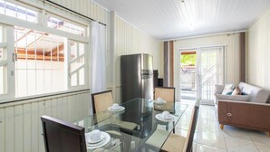 A dining area with a glass table and chairs, a refrigerator, and a sofa. - House w/ Barbecue 600 m From the Beach Nus0636 (Picarras)
