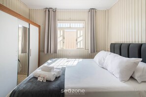 Ein Hotelzimmer mit Bett, einem Fenster mit Vorhängen und Blick nach außen.