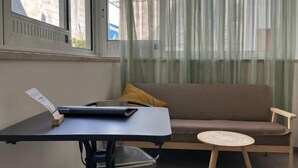 Un salon moderne avec un canapé, une petite table ronde et une table à manger avec des chaises.