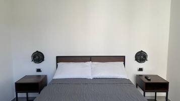 Un dormitorio con una cama, dos mesitas de noche y dos lámparas de pared.