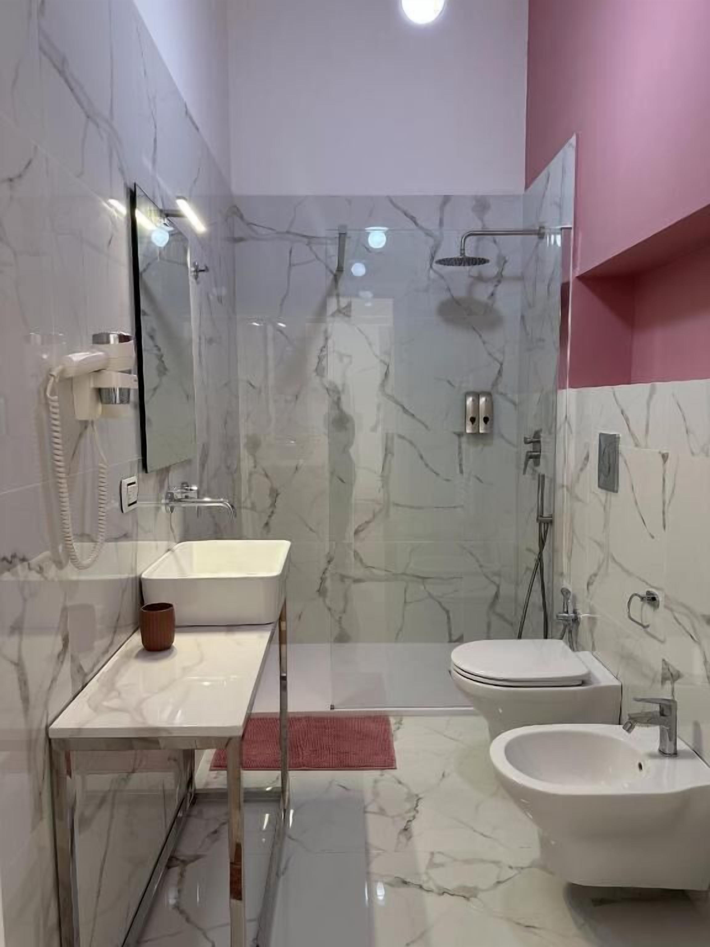 A modern bathroom with a marble vanity, a bidet, and a glass-enclosed shower.