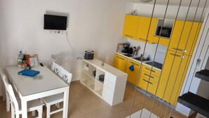 Eine kleine Küche mit gelben Schränken, einer weißen Arbeitsplatte und einem Essbereich mit Tisch und Stühlen.