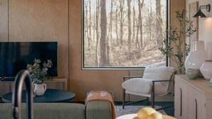 Una cocina moderna con un ventanal amplio, una zona de comedor con mesa y sillas, y un televisor sobre un mueble.
