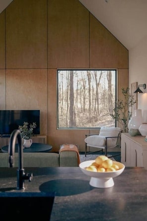 A modern kitchen with a large window, a dining area with a table and chairs, and a TV on a stand. - Modern Hideaway Retreat w Sauna (Gilmer County)