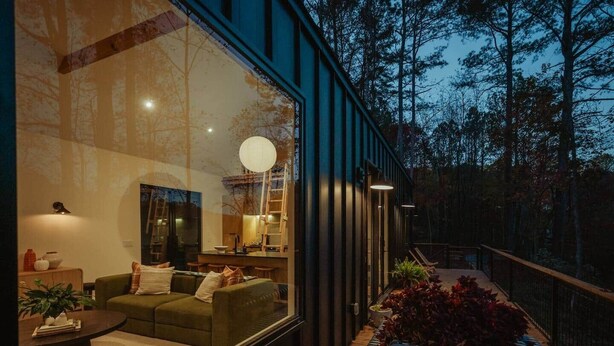 Un interior moderno con un sofá, un comedor y vistas a un bosque.