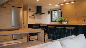 Une cuisine moderne avec des meubles en bois, un îlot central doté de tabourets et un coin repas comprenant une table et des chaises.