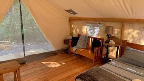 A tent with a bed, a bench, and a table.