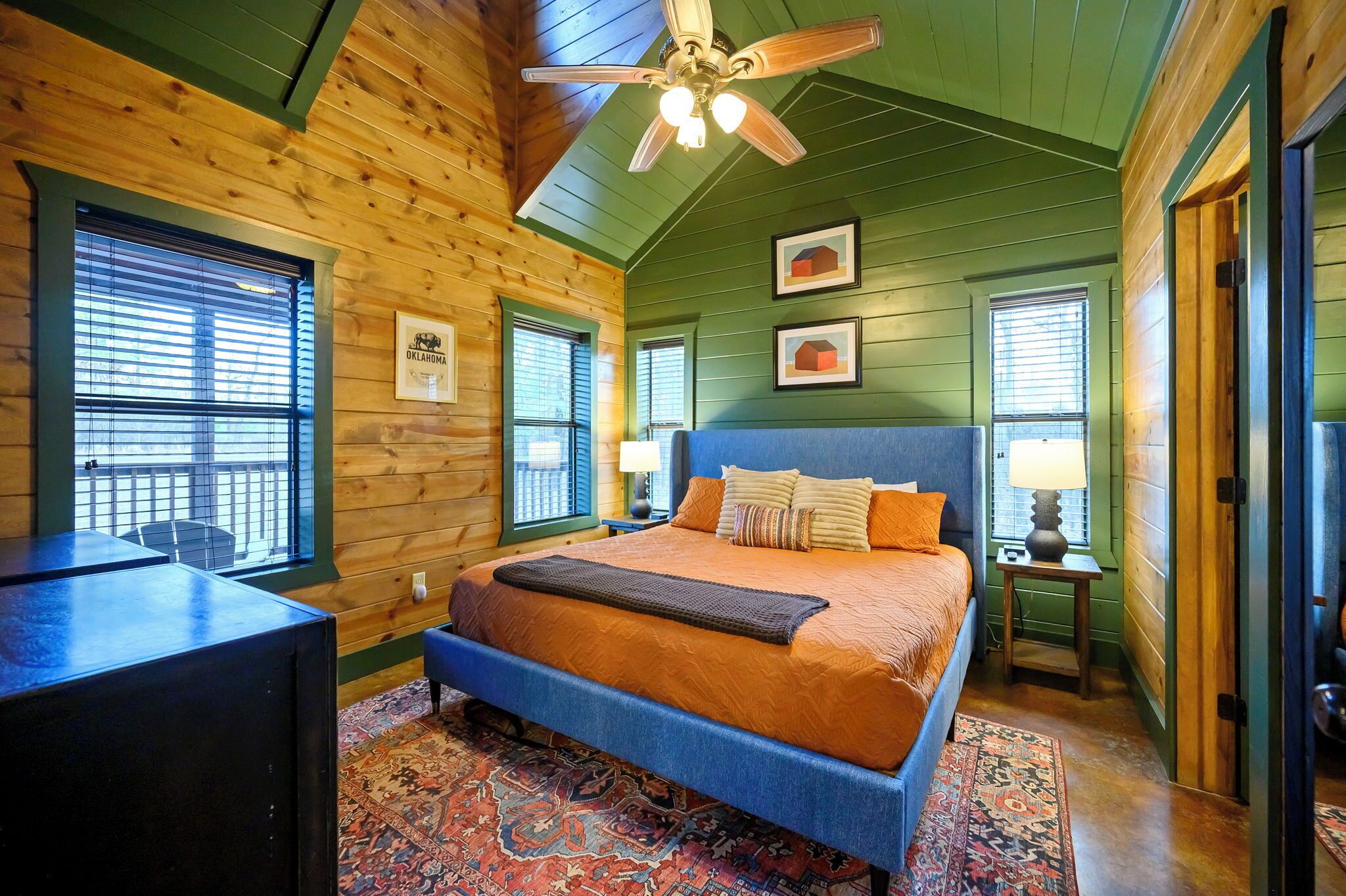 A bedroom with a large bed, a desk, and a ceiling fan.