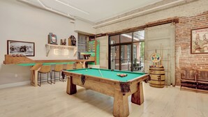 A pool table in a room with a brick wall, a billiards rack, and a bar area. - Pythian Studio #103-Walking distance to downtown Hot Springs & 6 min to Oaklawn! (Hot Springs)