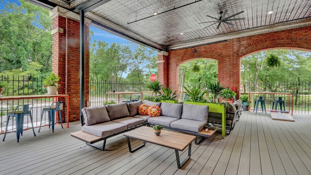 A covered outdoor seating area with a sofa, chairs, and a table, surrounded by brick walls and potted plants. - Pythian Studio #103-Walking distance to downtown Hot Springs & 6 min to Oaklawn! (Hot Springs)