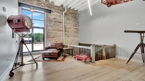A room with a leather sofa, a red toy car, a tripod, and a vintage camera. - Pythian Studio #103-Walking distance to downtown Hot Springs & 6 min to Oaklawn! (Hot Springs)