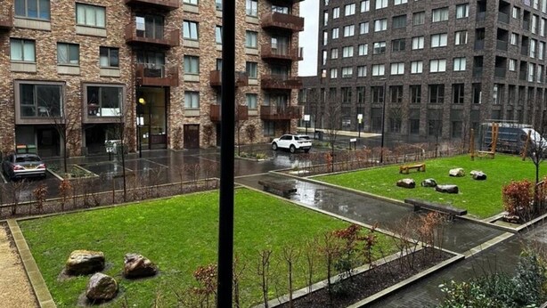 A residential building with multiple balconies, a parking area, and a small grassy courtyard with rocks. - townhouse 20 (London)