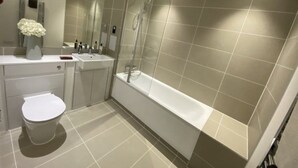 A modern bathroom with a bathtub, toilet, and vanity. - townhouse 20 (London)