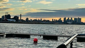 A waterfront view of a city skyline with buildings and a plane on the runway. - townhouse 20 (London)