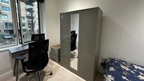 A bedroom with a bed, a desk, a chair, a wardrobe, and a window. - townhouse 20 (London)