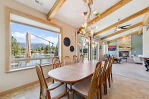 A dining area with a large wooden table, chairs, and a view of a marina.