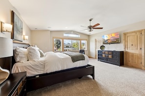 A bedroom with a bed, a dresser, a TV, and a ceiling fan.