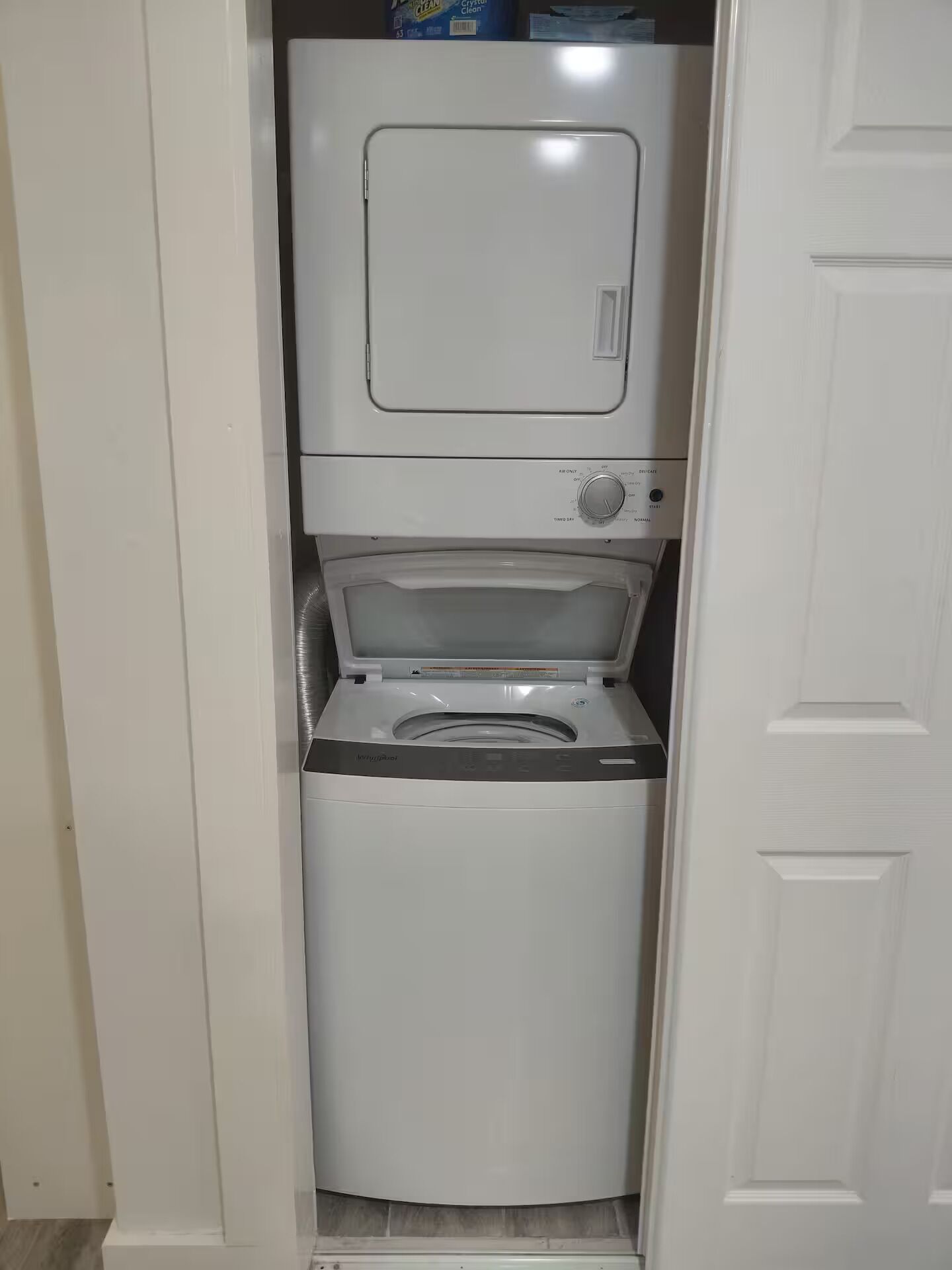 A compact, white laundry room with a front-loading washer and dryer.
