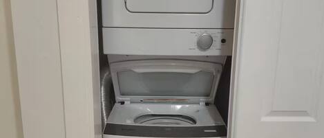 A compact, white laundry room with a front-loading washer and dryer.
