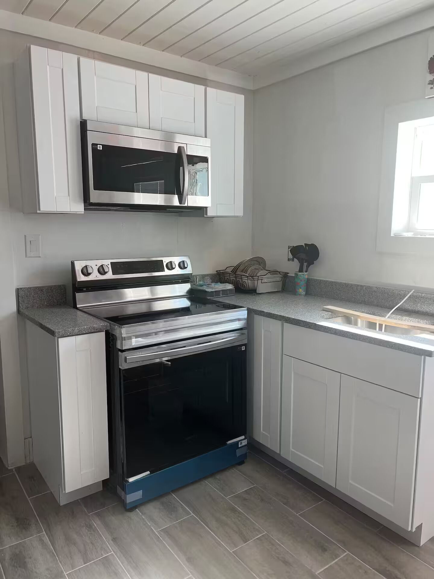 A kitchen with white cabinets, a stainless steel oven, and a microwave.
