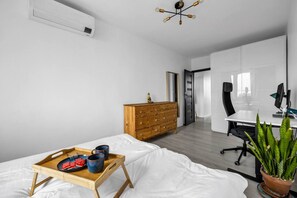 Et moderne soveværelse med en trækommode, et spisebord med bakke og et skrivebord med stol.