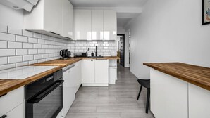 Una cocina moderna con armarios blancos, encimera de madera y una silla negra.