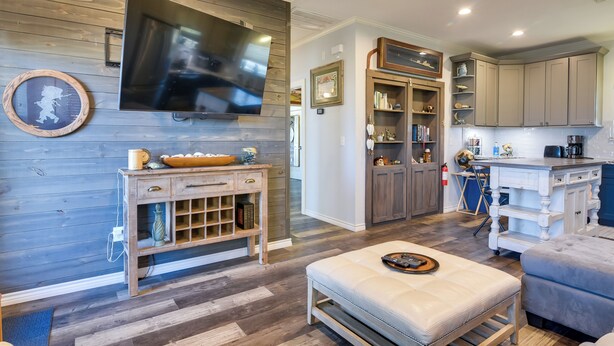 A modern kitchen with a large flat-screen TV, wooden cabinetry, and a built-in island with a coffee machine. - Group-Friendly Hot Tub Haven in Galveston! (Galveston)
