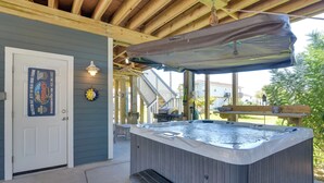 A hot tub under a covered patio with a wooden ceiling, a door with a sign, and a small bench. - Group-Friendly Hot Tub Haven in Galveston! (Galveston)