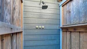 A wooden exterior wall with a metal showerhead and three light switches. - Group-Friendly Hot Tub Haven in Galveston! (Galveston)