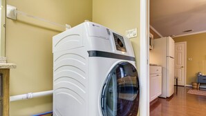 Een voorlader wasmachine in een wasserij met houten vloeren en een deur naar een andere ruimte.