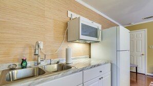 Een keuken met een dubbele spoelbak, een magnetron en een koelkast.
