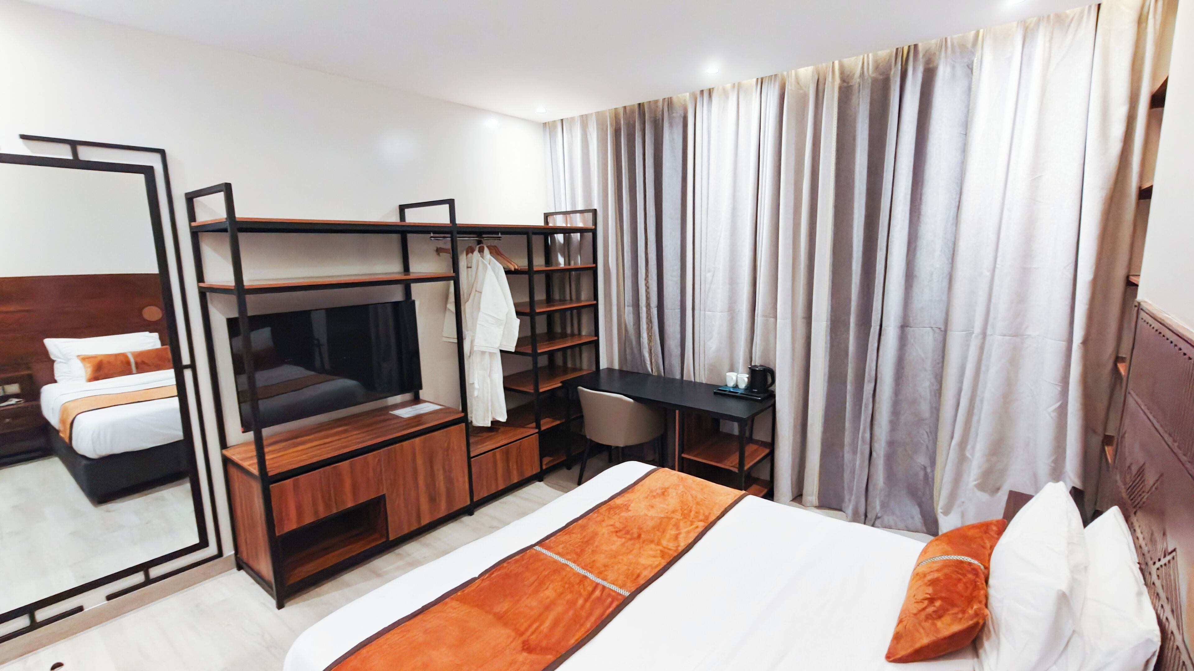 Una camera d'albergo con un letto a castello, una scrivania, una sedia, un armadio e un grande specchio.