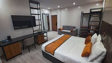 Una habitación de hotel moderna con cama, escritorio, silla, televisor, armario y zapatero.