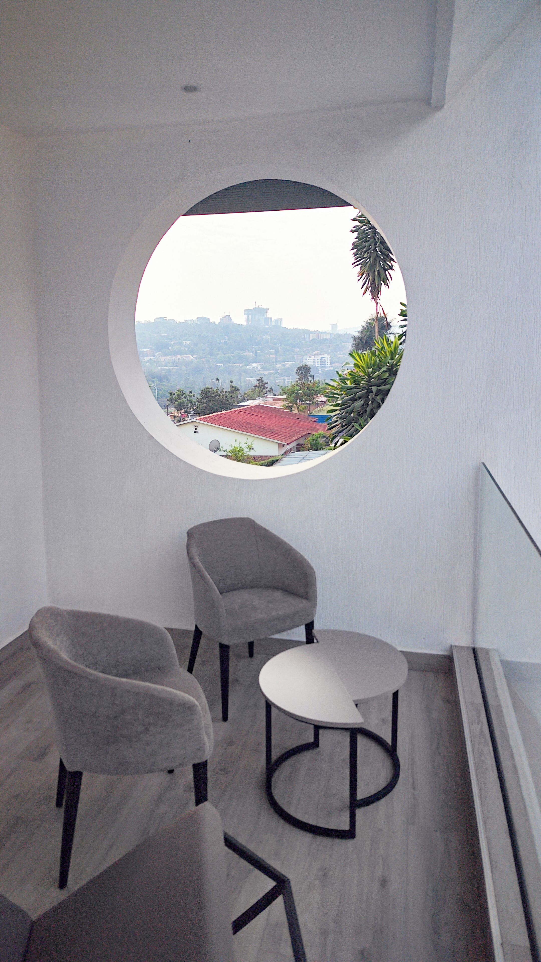 A balcony with a circular window, two armchairs, and a small table.