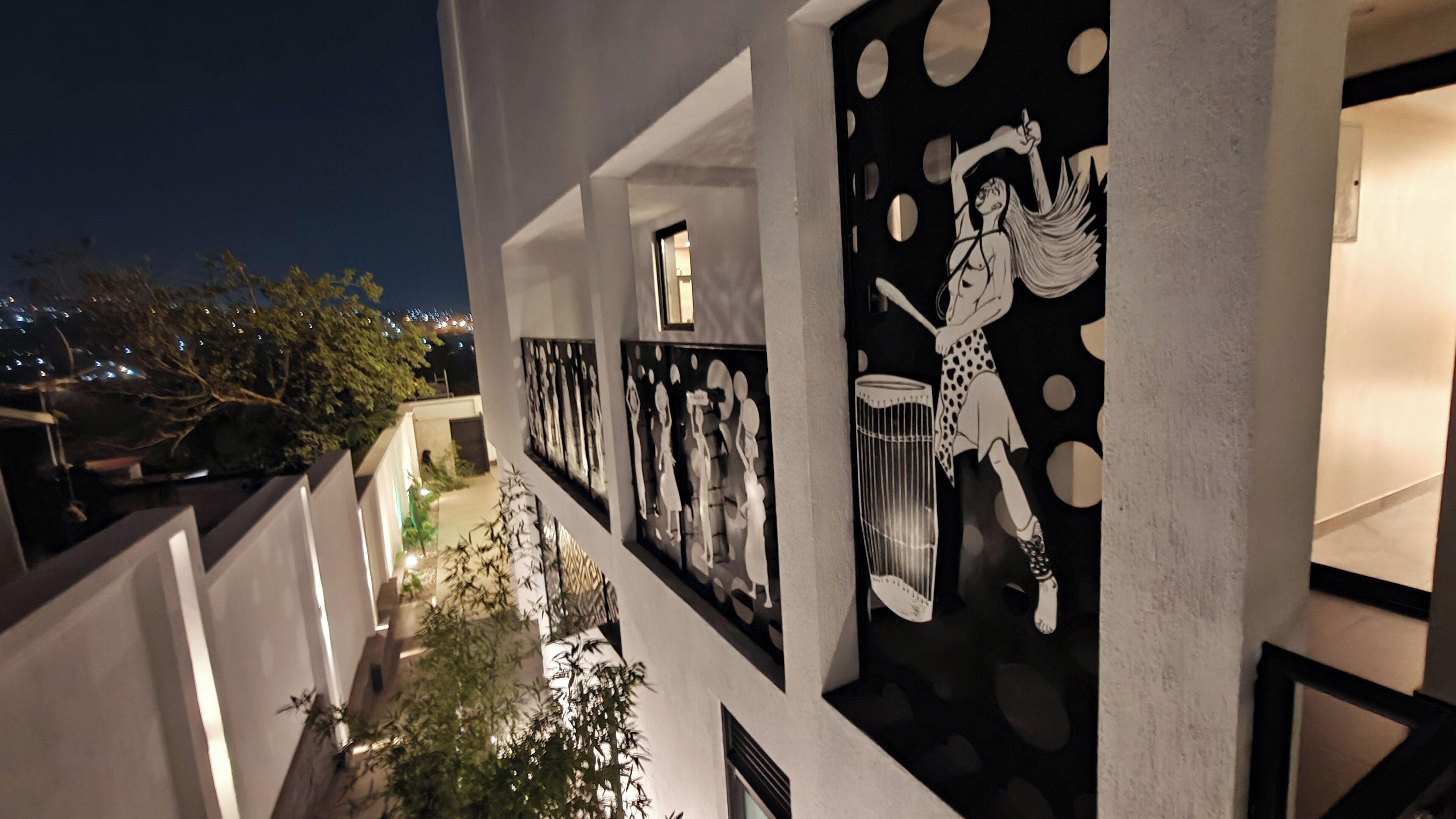 Un bâtiment moderne doté d’un balcon donnant sur une vue panoramique de la ville la nuit.