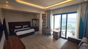 Una habitación de hotel moderna con una cama grande, un escritorio, una silla y un balcón con vistas.