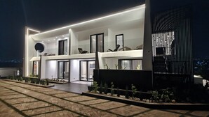 Un edificio moderno de varios pisos con un amplio espacio exterior, ventanas grandes y una entrada bien iluminada.