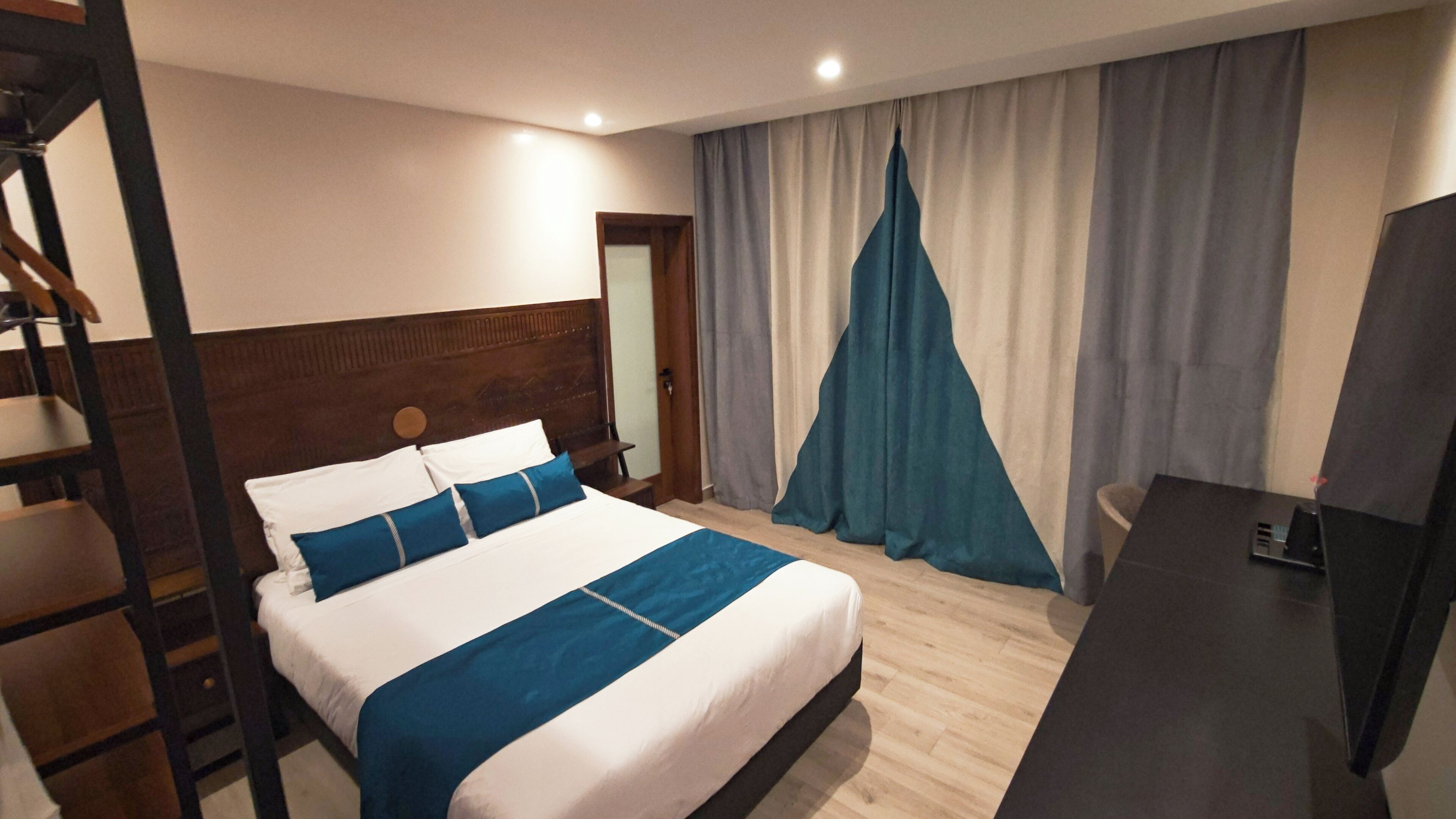 A hotel room with a bed, a desk, and a TV.