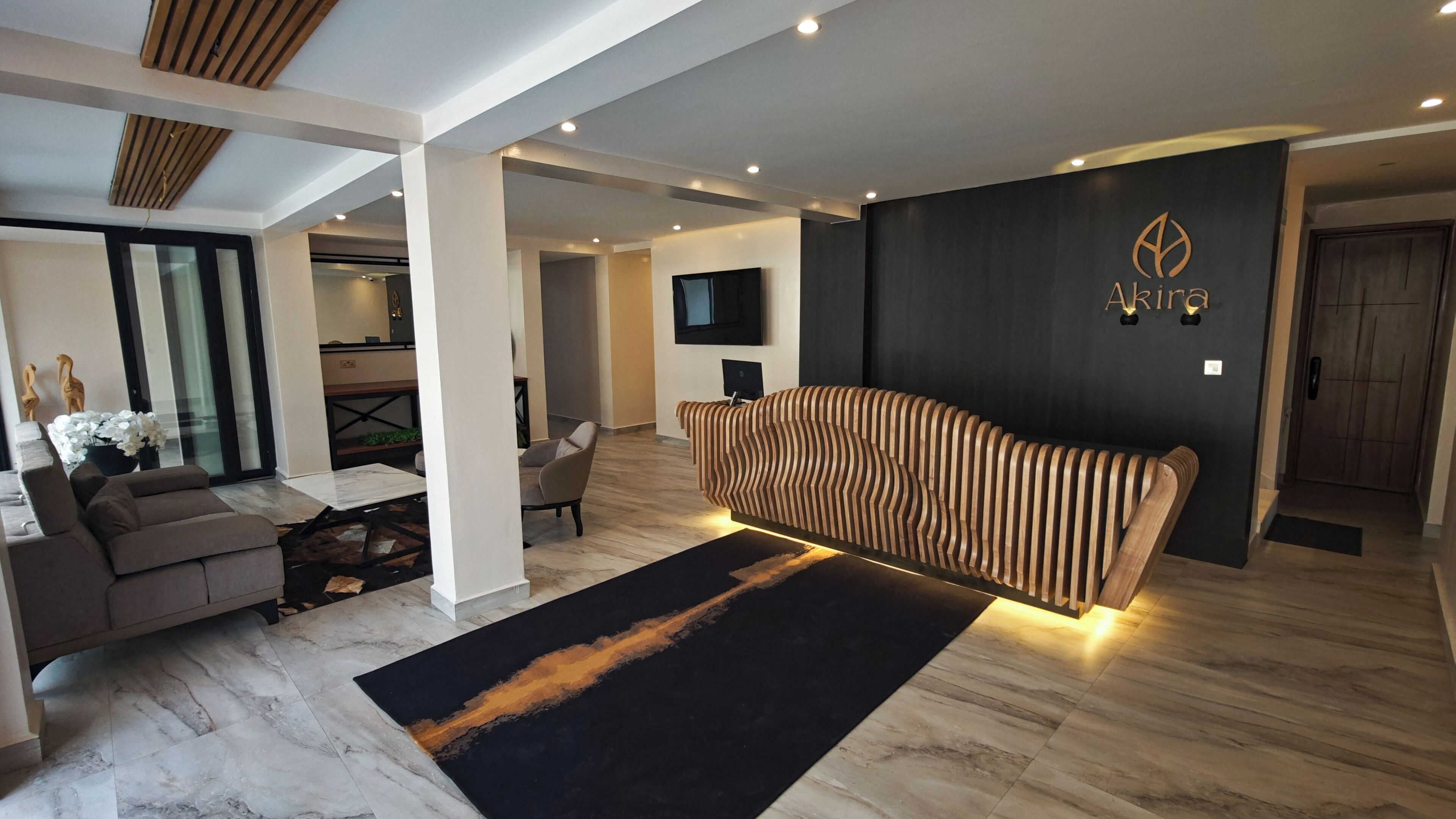 A modern interior with a reception desk, a sofa, a TV, and a wooden accent wall.