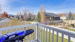 A blue motorcycle on a balcony with a view of a residential neighborhood and mountains in the background. - Park City Area Lodge: 9 Mi to Timber Lakes (Heber City)