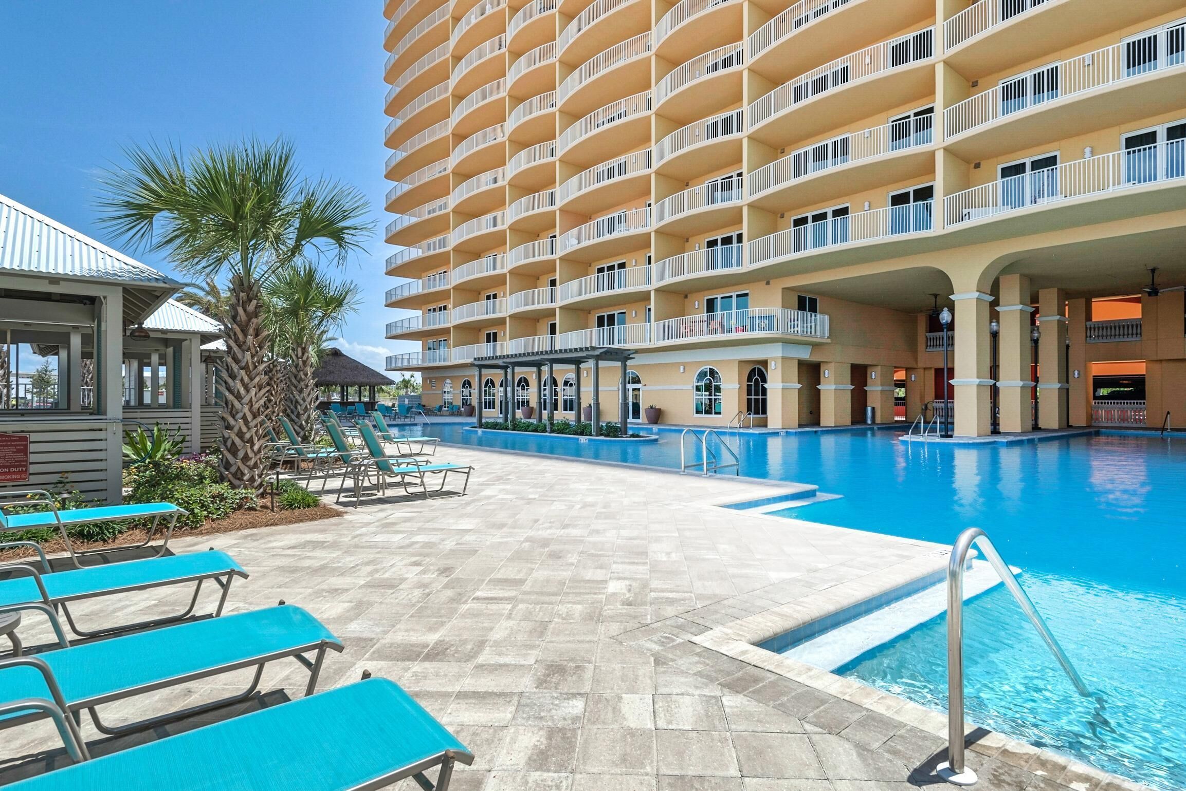 A hotel with a large pool, multiple balconies, and outdoor seating areas.