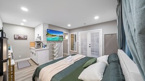 A bedroom with a bed, a TV, a kitchenette, and a bathroom. - Modern Studio w King Bed, Full Kitchen, Gated Yard (Spring Valley)