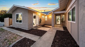 A modern house with a covered patio, a landscaped garden, and a clear view of the sunset. - Modern Studio w King Bed, Full Kitchen, Gated Yard (Spring Valley)