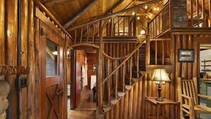 Interior de madera con una escalera, paredes de madera y una lámpara.
