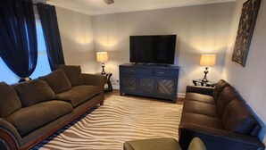 A living room with a ceiling fan, two sofas, a television, and a zebra-patterned rug.