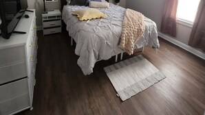 A bedroom with a bed, a ceiling fan, a dresser, a mirror, and a window with curtains.